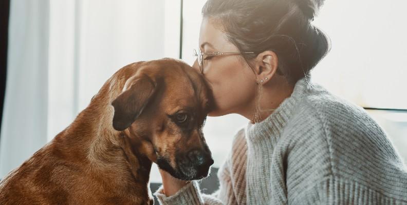 An owner kissing her dog