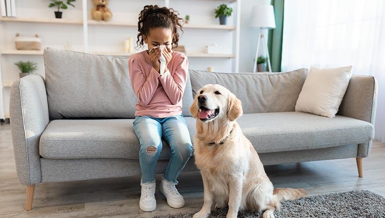 A woman sneezing next to her dog because of allergies